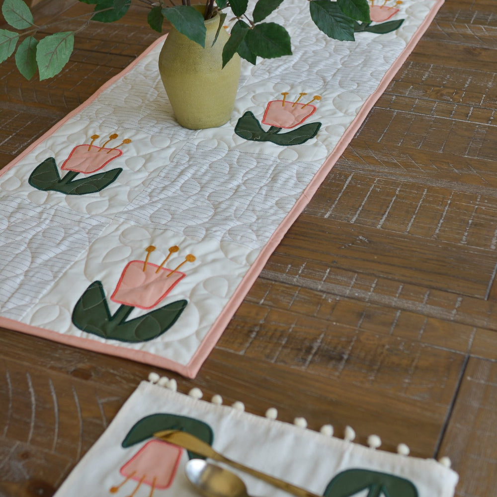 Floral table runner with a vase of flowers on a wooden table