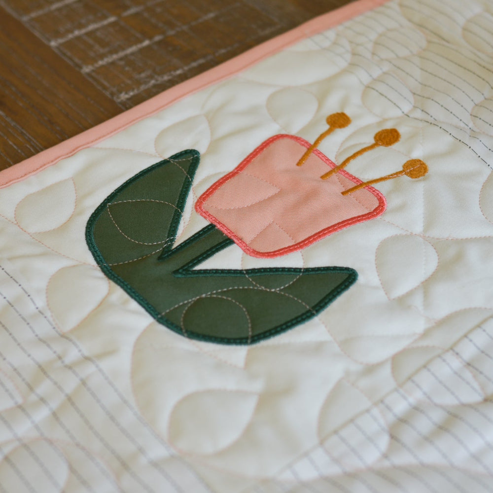 Quilted fabric with a pink tulip design on a wooden surface