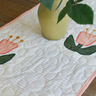 Floral-patterned table runner with a green vase on a wooden surface