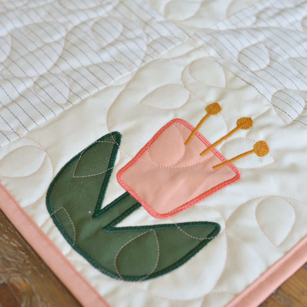 Quilted fabric with a pink tulip design on a wooden surface