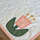 Quilted fabric with a pink tulip design on a wooden surface