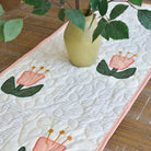Quilted table runner with floral design on a wooden surface