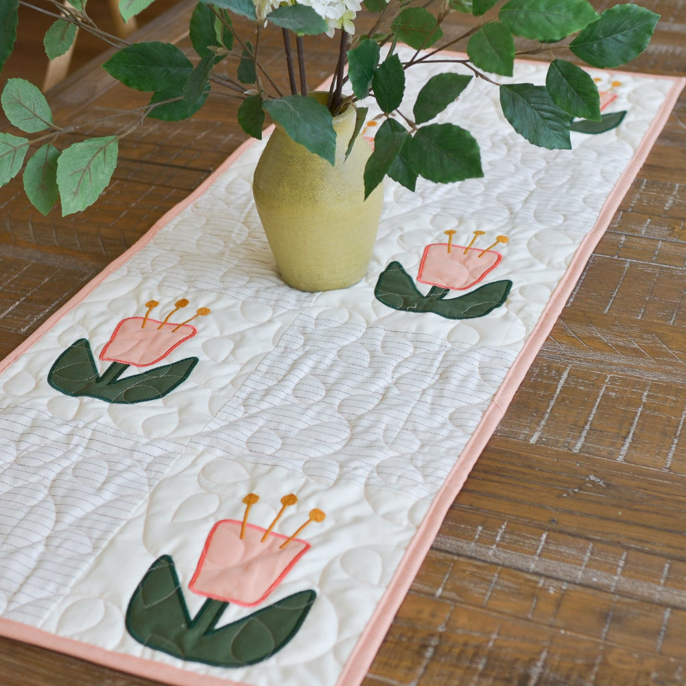 Quilted table runner with floral design on a wooden table