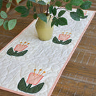 Quilted table runner with floral design on a wooden table