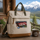 Beige backpack with Montana design on a wooden table with a scenic background