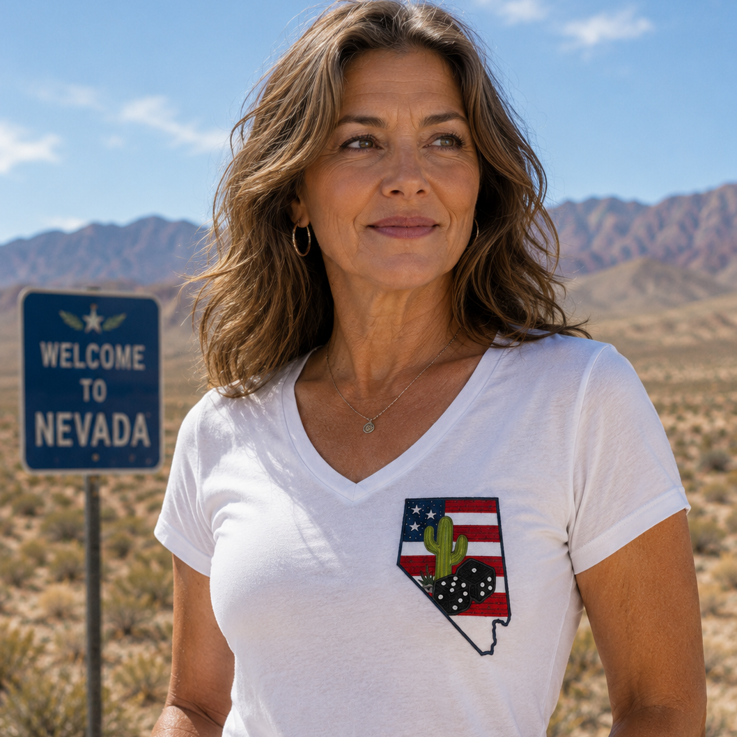 Woman wearing a white t-shirt with a Nevada state design in a desert landscape with a 'Welcome to Nevada' sign.