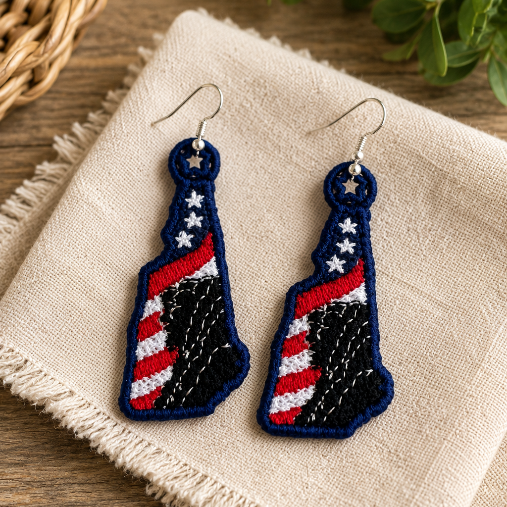 Pair of blue earrings with American flag design on a beige cloth with green leaves in the background