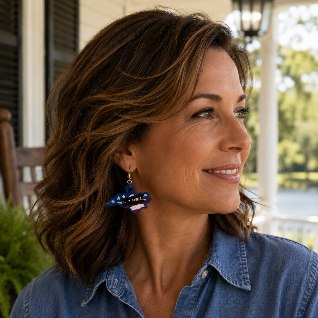 Woman wearing a blue denim shirt with earrings, standing outdoors.