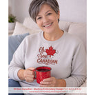 Woman wearing a 'Oh Sew Canadian' sweatshirt holding a red mug.