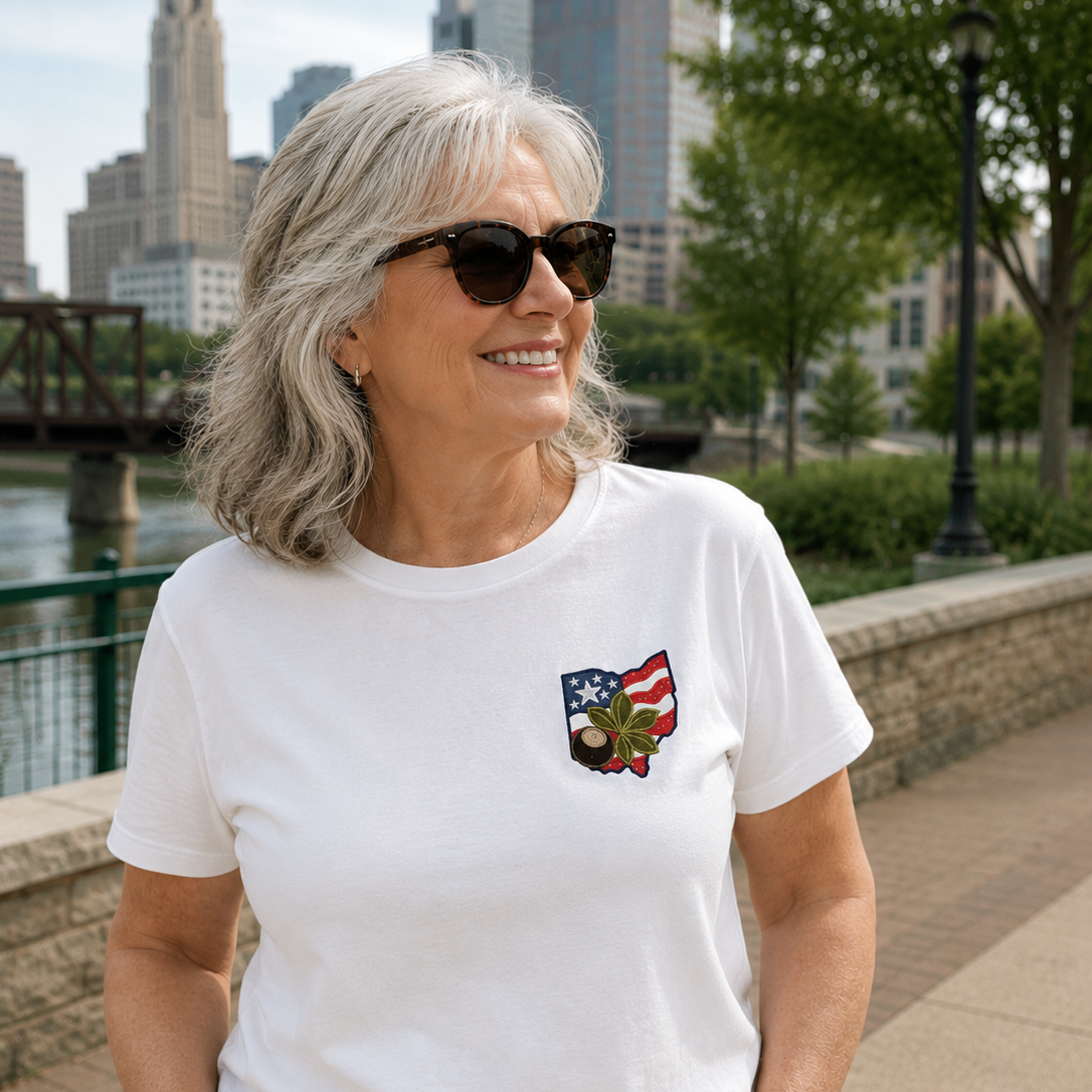 Woman wearing a white t-shirt with a pocket design, standing outdoors with a cityscape in the background.