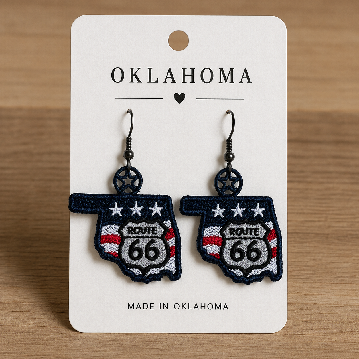 Pair of earrings shaped like the state of Oklahoma with Route 66 design on a card labeled 'Made in Oklahoma'.