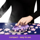 Person using a purple iron on a floral ironing board with 'oliso' branding.