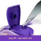 Purple water bottle with open cap being filled with water on a white background