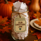 Glass jar labeled 'Our Gratitude Jar' with autumn leaves and pumpkins in the background
