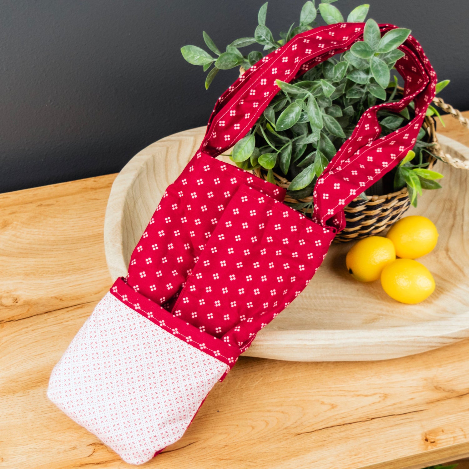 Red patterned cloth wrapped around a plant on a wooden surface with lemons.