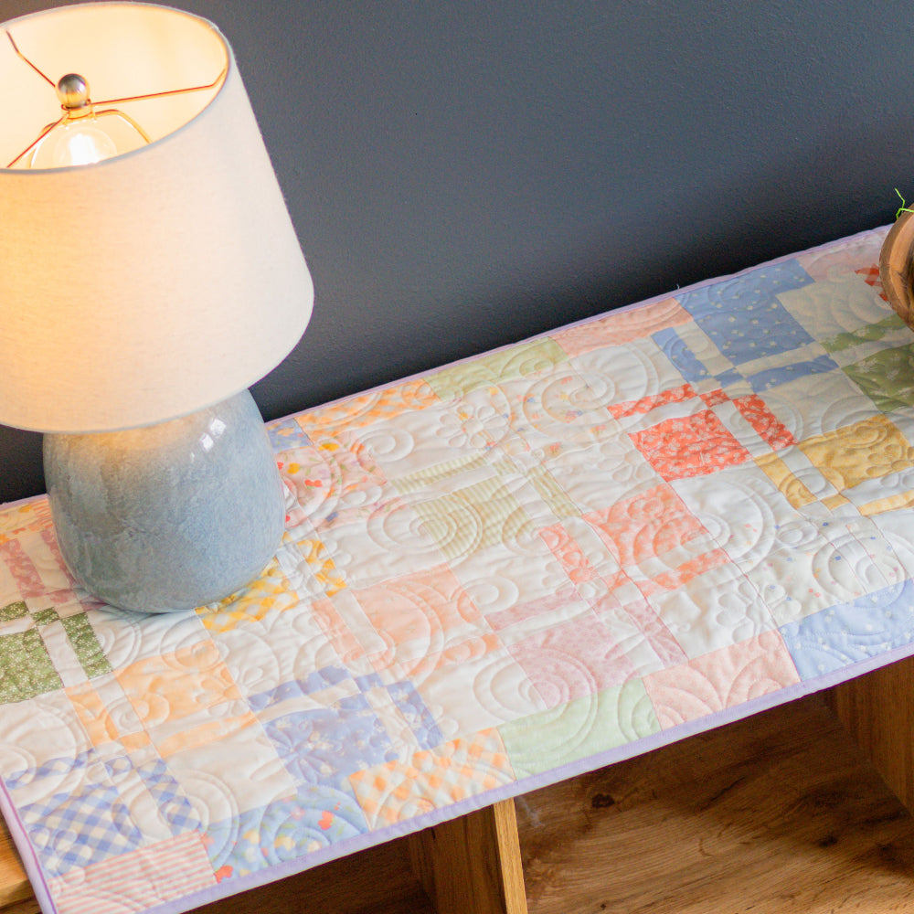 Colorful quilted table runner on a wooden table with Easter decorations.