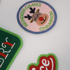 Three embroidered patches on a white background, including a reindeer patch, a green patch with a logo, and a red 'Nice' patch.