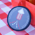 Round utensils holder with American flag design on a red and white checkered tablecloth.
