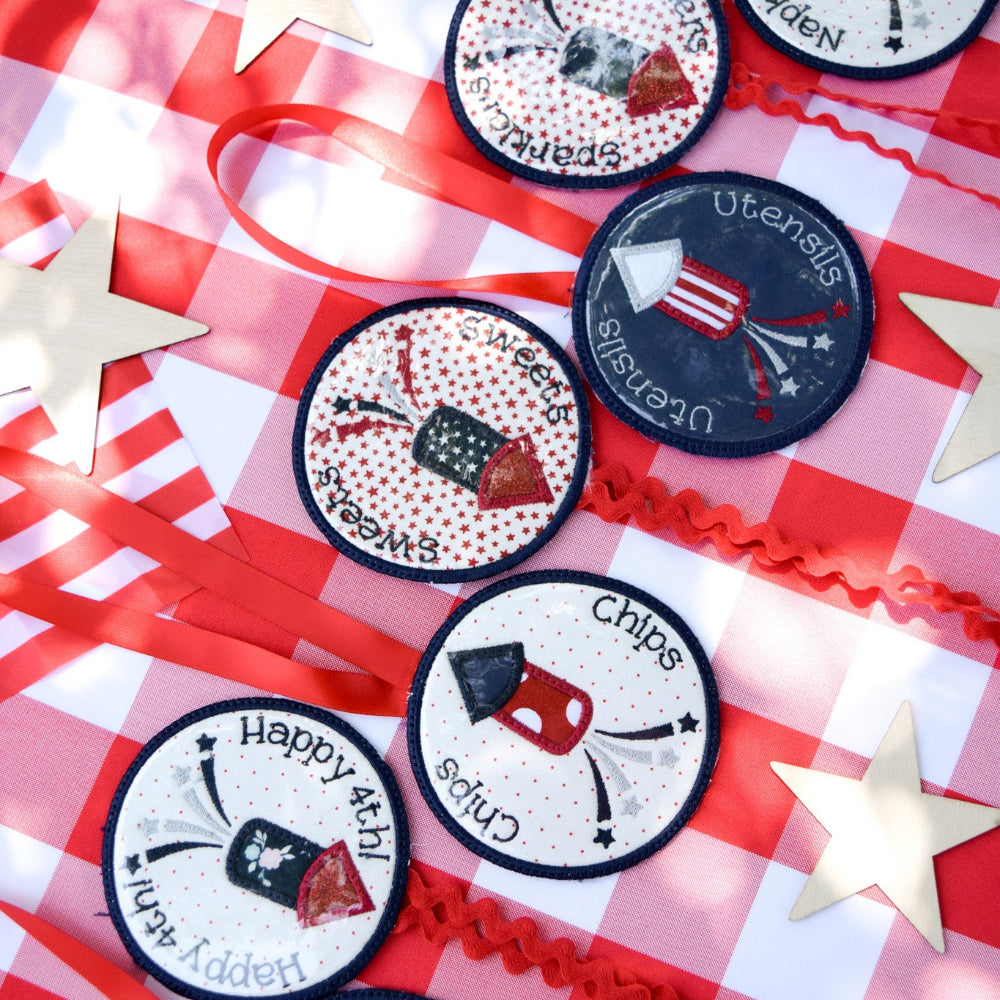 Set of round labels with various designs on a red and white checkered tablecloth.