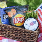 Basket with Lay's potato chips and Doritos on a checkered tablecloth outdoors
