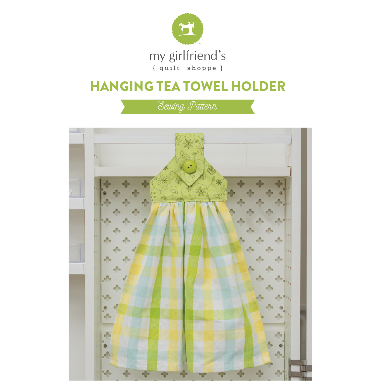 Hanging tea towel holder with green top and plaid pattern on a white background, featuring 'my girlfriend's quilt shoppe' branding.
