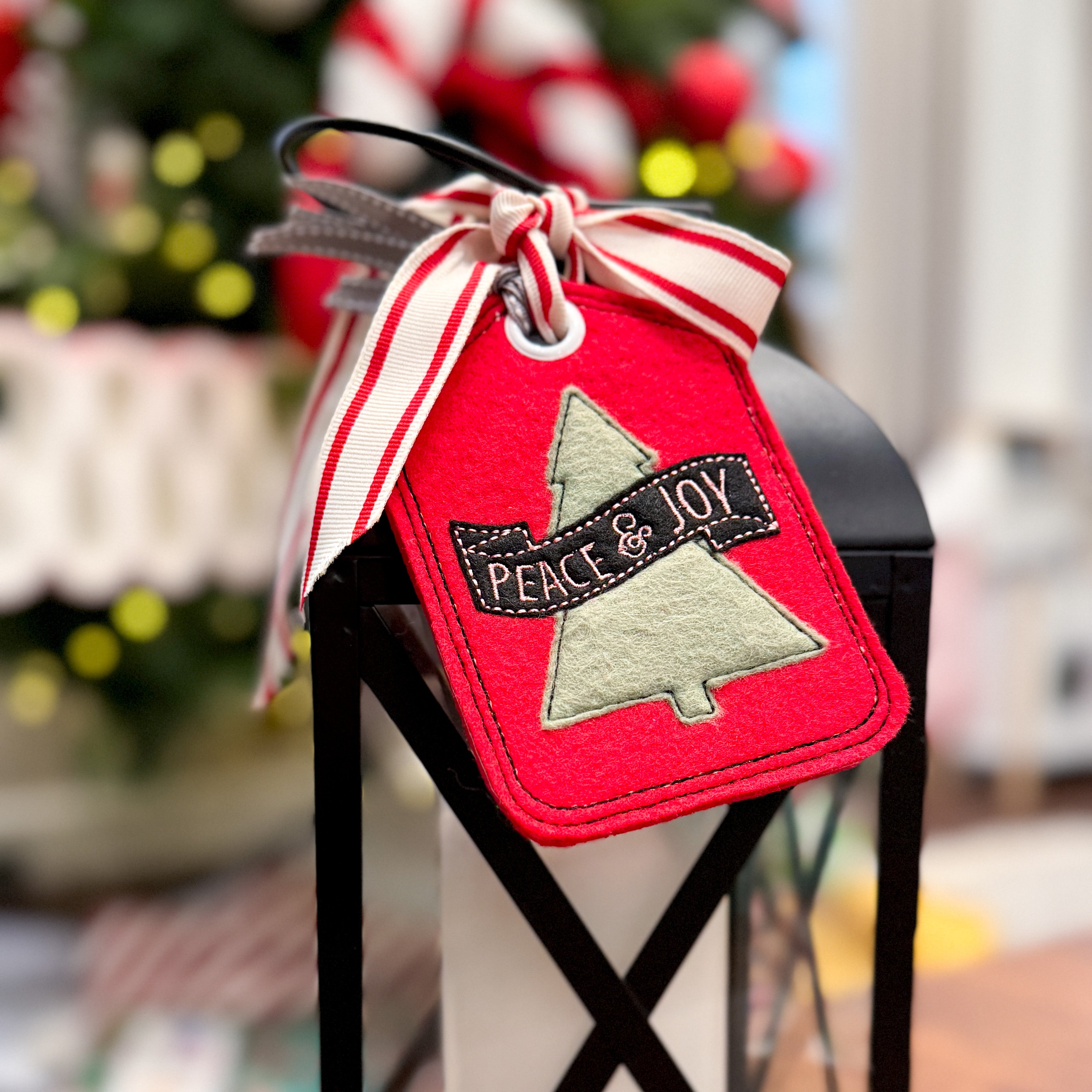 Decorative Christmas tag with 'Peace & Joy' text on a candle in a black lantern.