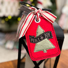 Red Christmas tag with 'Peace & Joy' text and tree design, tied with a ribbon.