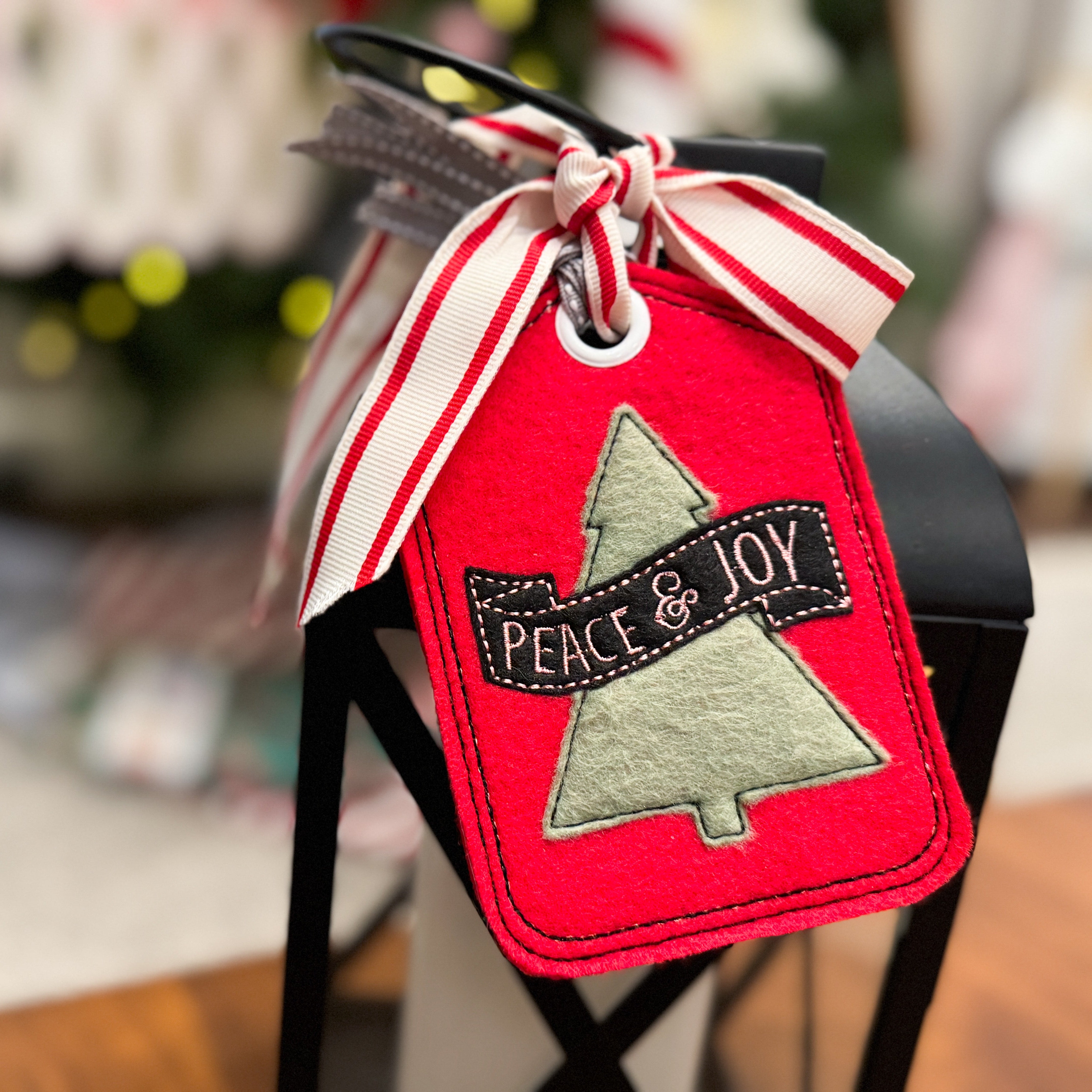 Red Christmas tag with 'Peace & Joy' text and tree design, tied with a ribbon.