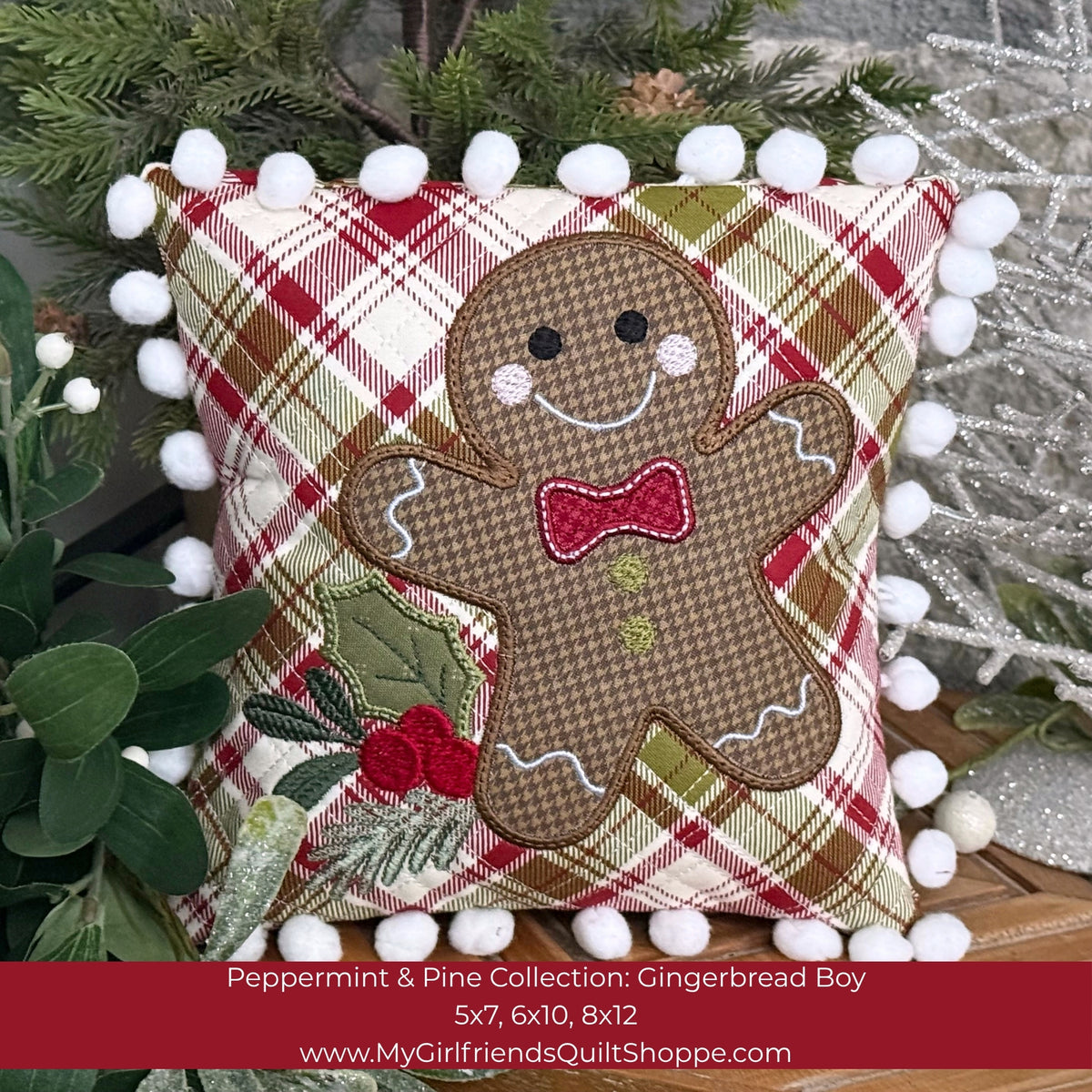 A square decorative quilted pillow with a gingerbread boy applique on a red, green, and cream plaid fabric background, finished with white pom-pom trim. A red banner at the bottom displays product details for the 'Peppermint Pine Collection: Gingerbread Boy'.