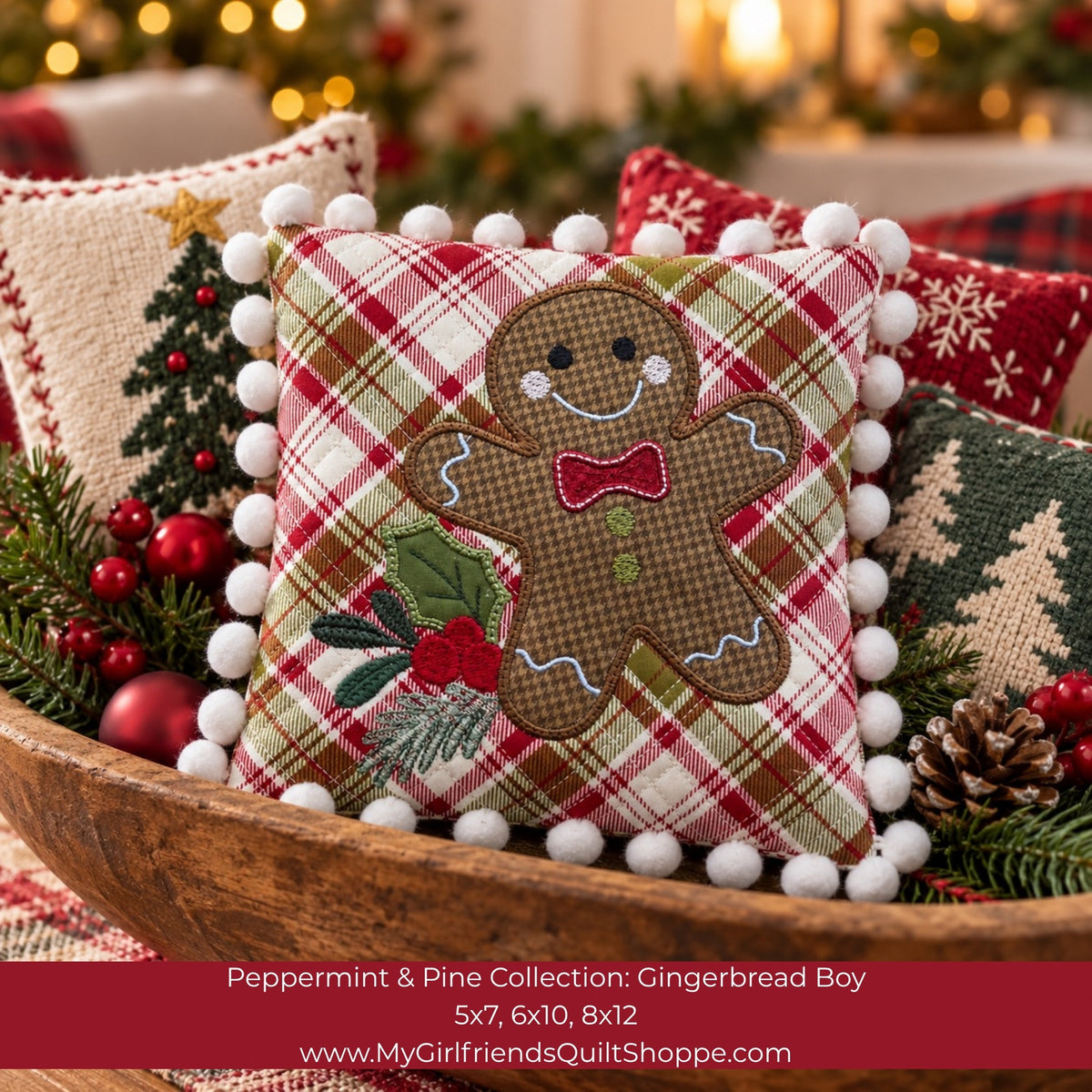 A festive Christmas throw pillow featuring a gingerbread boy applique on a red, green, and beige plaid background, surrounded by white pom-poms. The pillow is styled in a wooden bowl with other holiday pillows and greenery, with a warm blurred background.