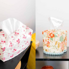 Two floral-patterned tissue boxes on a black surface with a white background