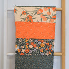 Floral-patterned quilt draped over a wooden ladder against a white wall