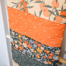 Quilt with floral and fruit patterns draped over a chair.