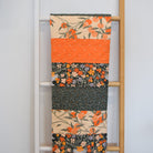 Quilt with floral and fruit patterns draped over a ladder