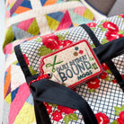 Floral-patterned bag with a decorative tag on a colorful quilted background
