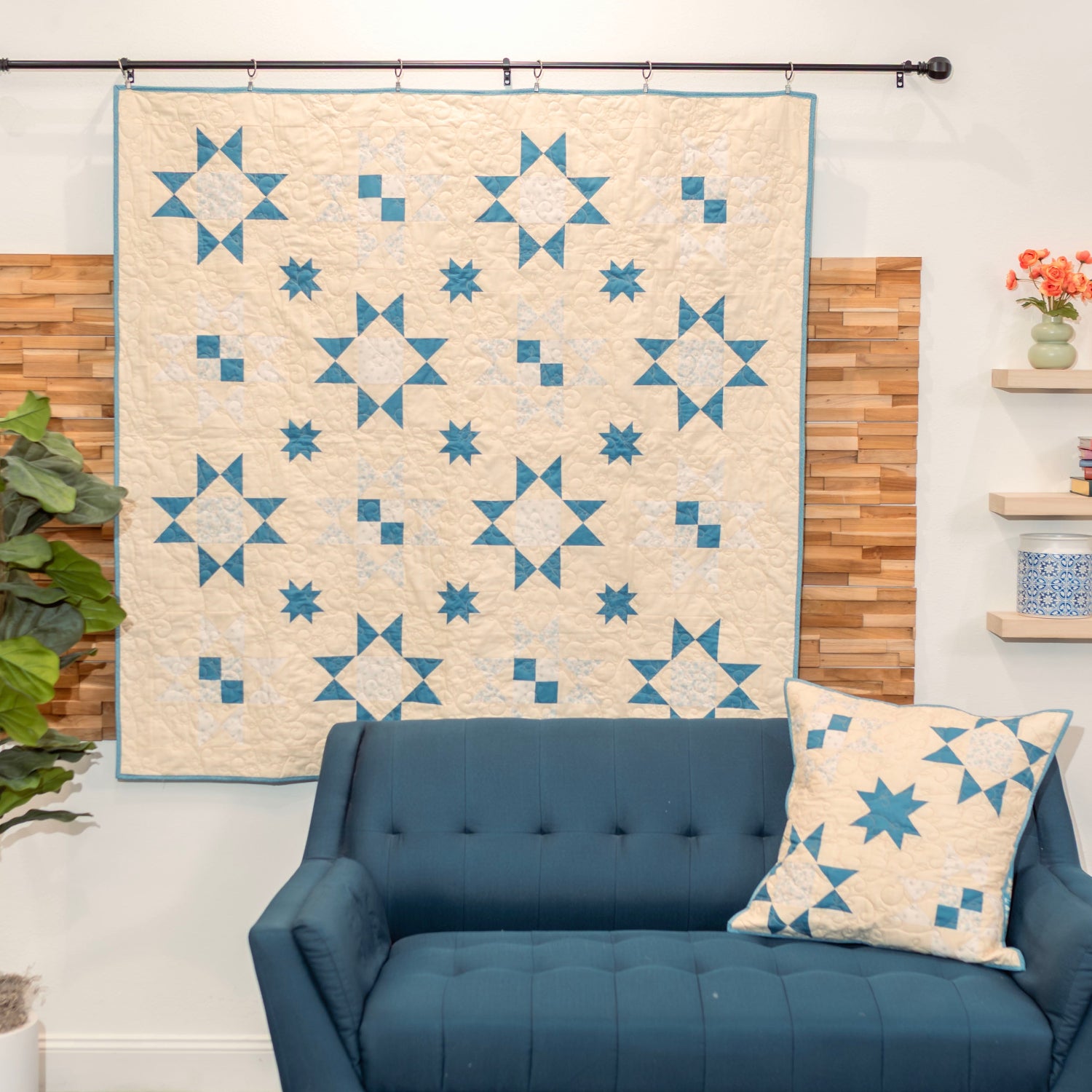 Blue sofa with a matching pillow in front of a wall with a star-patterned quilt.