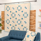 Blue sofa with a decorative pillow and a patterned quilt in the background