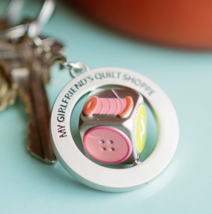 Keychain with spools of thread and buttons on a light blue background
