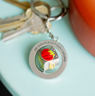 Keychain with a colorful charm and text on a light blue background