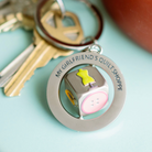 Keychain with 'My Girlfriend's Quilt Shoppe' text and quilt design on a light blue background