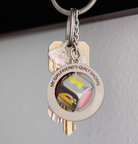Keychain with a small round tag and key-shaped charm on a neutral background
