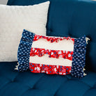 Three pillows on a blue couch: white, red, white, and blue pillow with floral patterns.