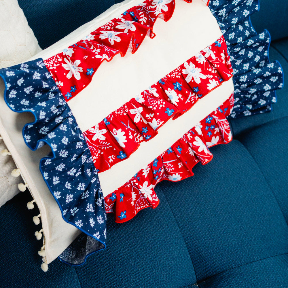 Decorative pillow with red, white, and blue pattern on a blue couch.
