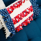 Decorative pillow with red, white, and blue pattern on a blue couch.