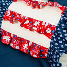 Red, white, and blue floral ruffled fabric on a cushion with a blue background.