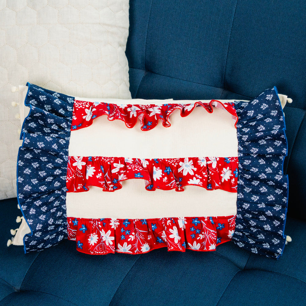 Decorative pillow with red, white, and blue pattern on a blue couch.