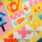 Colorful quilt with floral, butterfly, and carrot patterns on a blue fabric background.