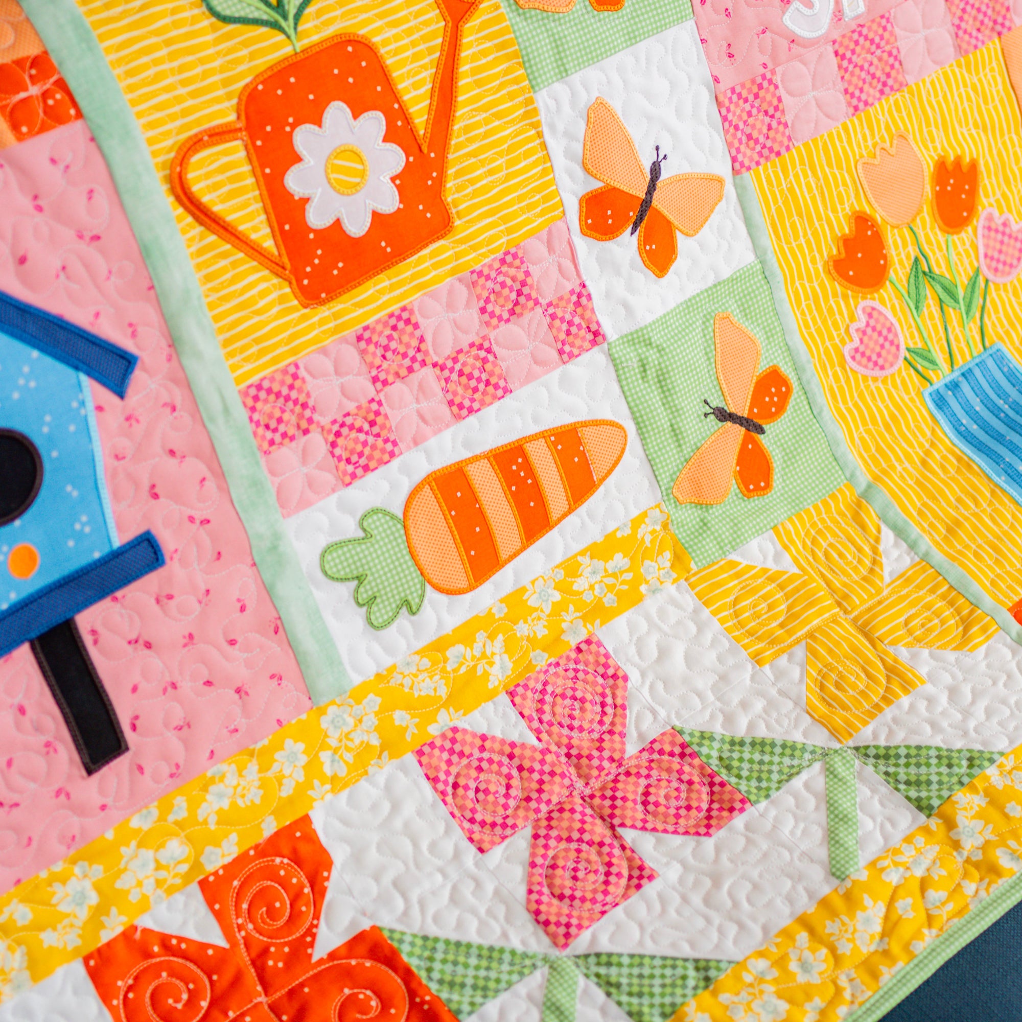 Colorful quilt with floral, butterfly, and carrot patterns on a blue fabric background.