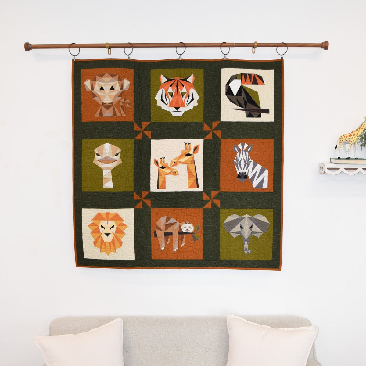 Quilt with animal illustrations hanging above a sofa