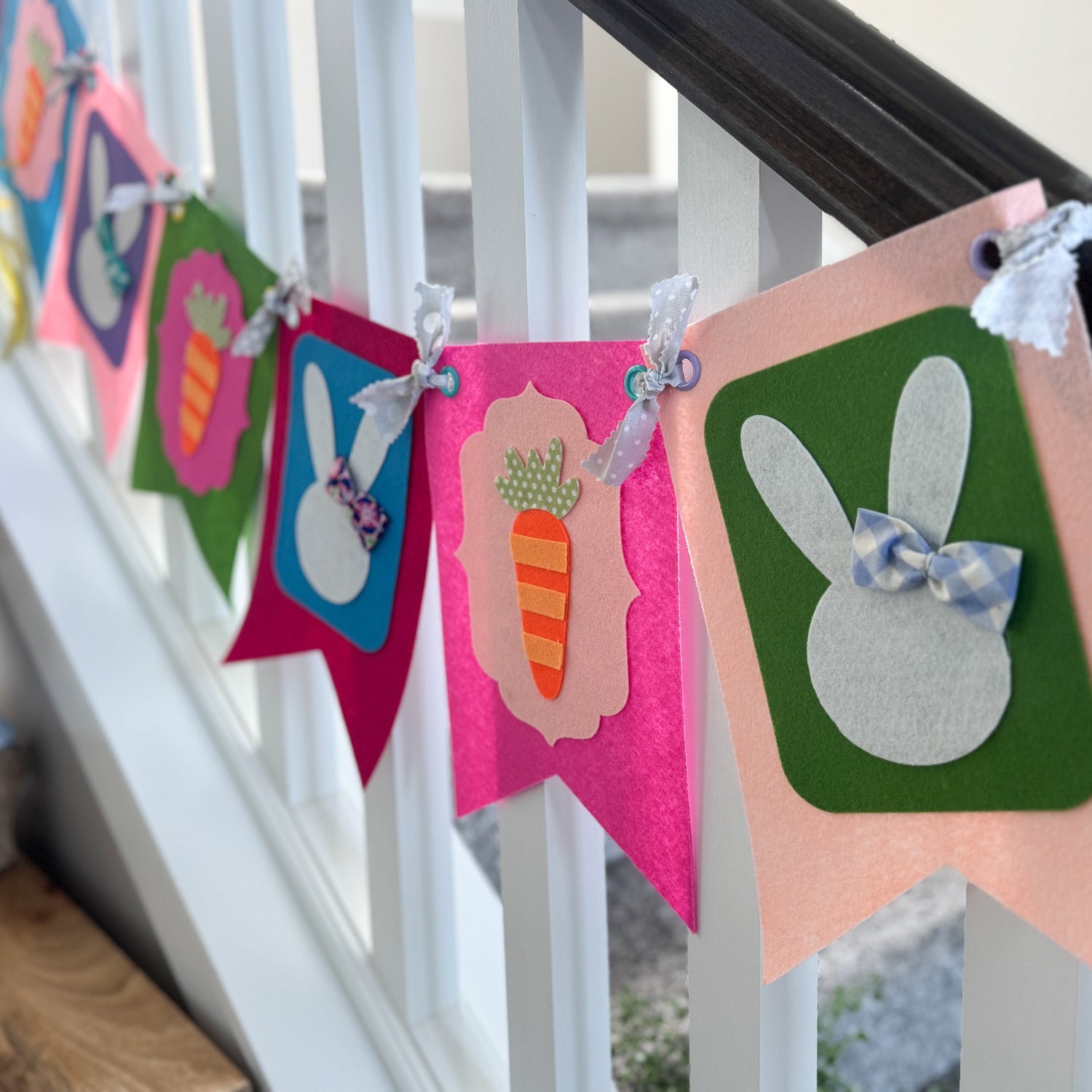 Colorful Easter-themed banner with bunnies and carrots hanging on a staircase.
